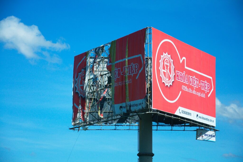 A partially destroyed billboard in Vietnam, against a bright blue sky.